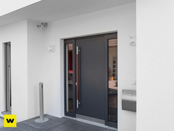 Moderne Haustür aus Aluminium mit Seitenteil und Edelstahlgriff an weißer Fassade
